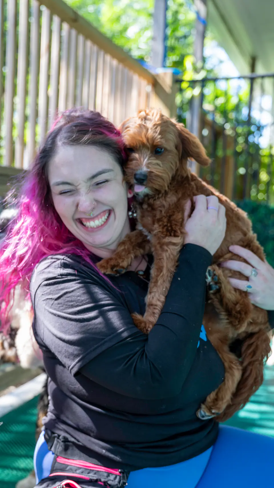 Dogtown trainer hugging a red doodle puppy